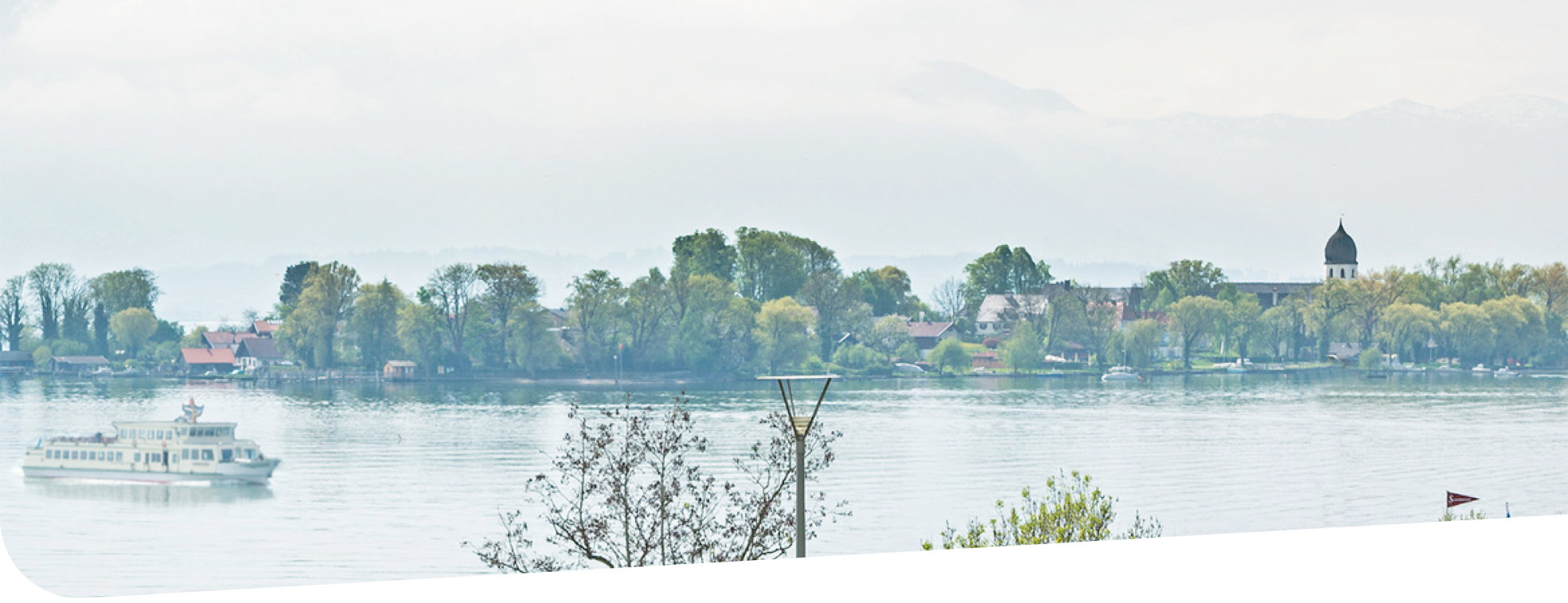 Der Chiemsee mit Schiffen im Hintergrund eine Insel mit Kirche